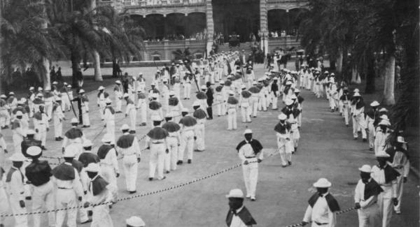 Funeral procession of Queen Liliʻuokalani with Native Hawaiian stevedores in white carrying her casket at ʻIolani Palace.
